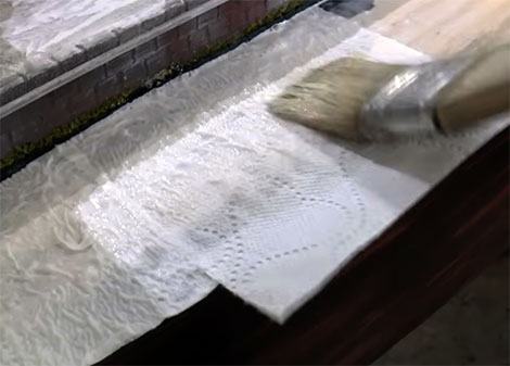 Placing sheets of toilet paper into the wet glue adding more glue on top